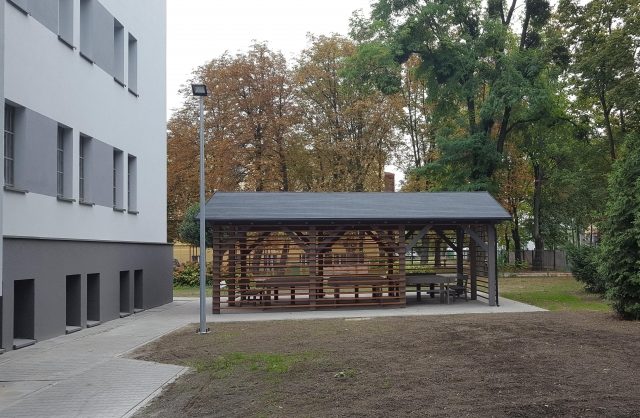 Zdjęcie przestawiające drewnianą altanę wybudowaną obok budynku
