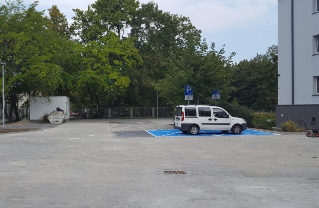 Zdjęcie przestawiające wyremontowany parking koło budynku